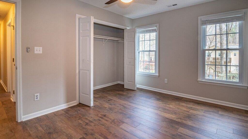 apartment move-in inspection of an empty bedroom with bare floor, open closet and daylight windows