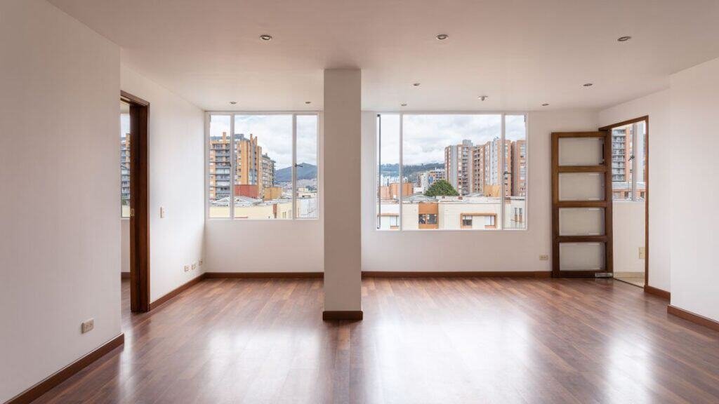the first apartment guide begins here: an empty sunlit living room with wood floors and city windows