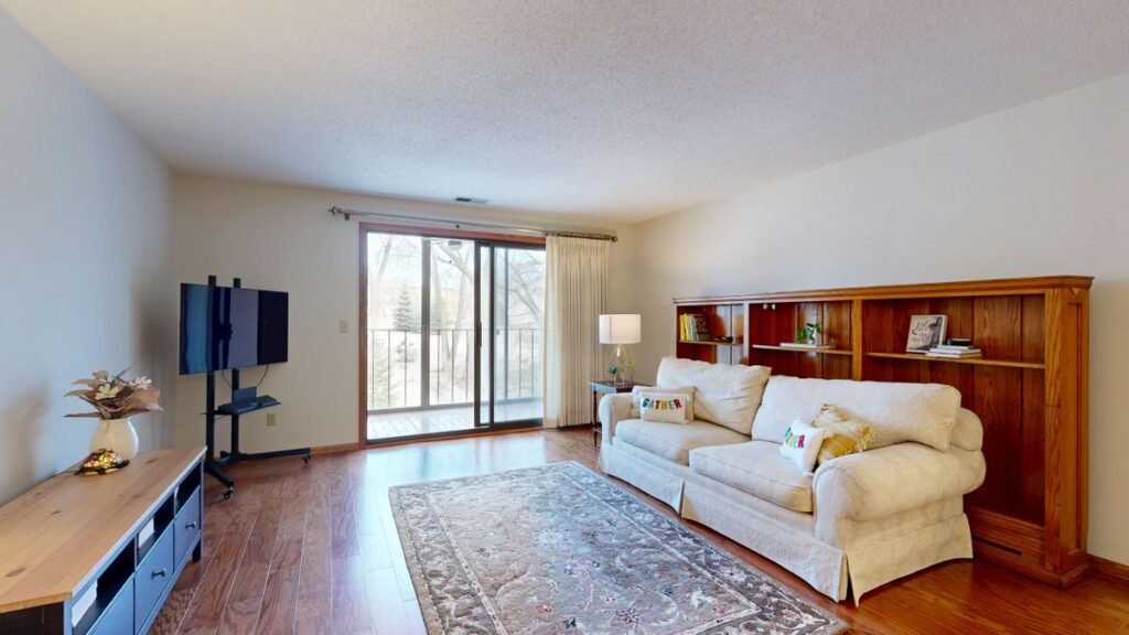 A bright, ordinary apartment living room with hardwood floors and a couch, representing the kind of rental space renters insurance covers