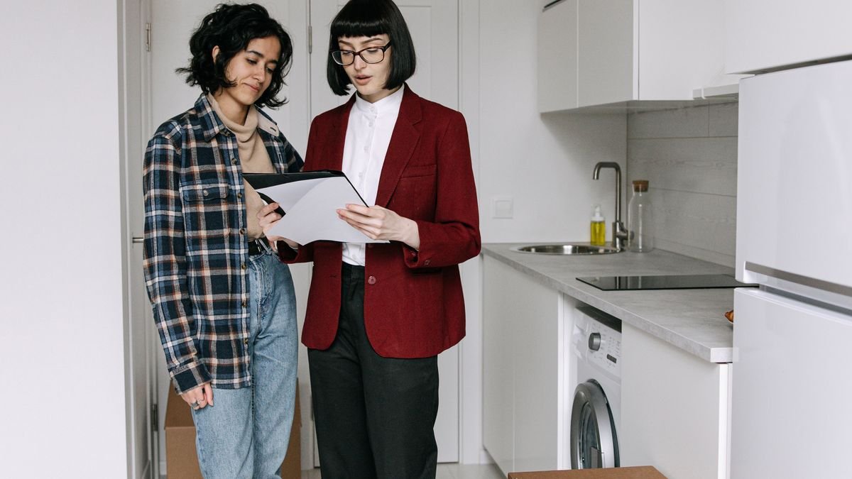 two renters going through lease paperwork in a kitchen with moving boxes