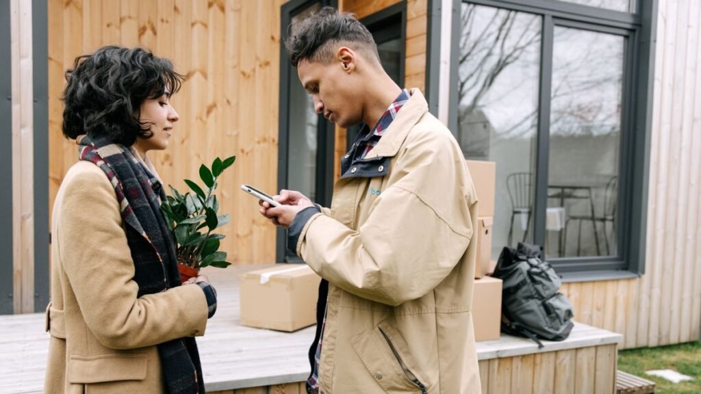 couple reviewing a rental listing on a phone while moving in, checking details carefully