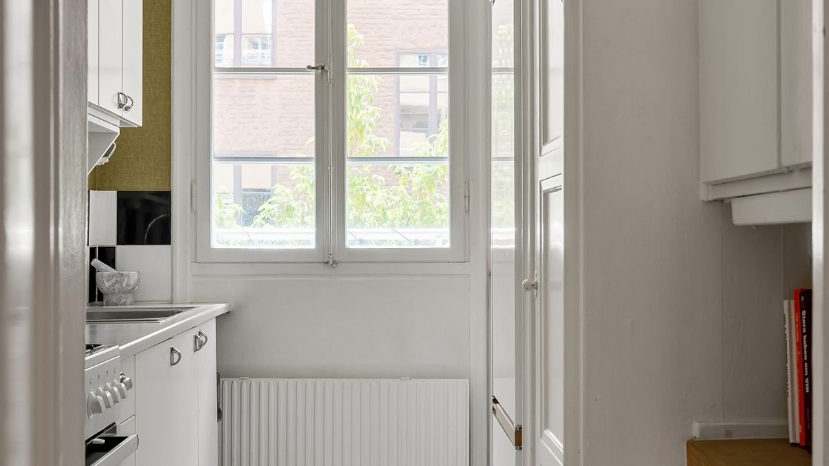 narrow apartment kitchen with a radiator below a bright window