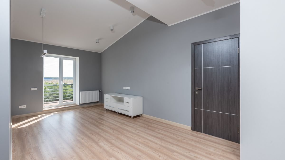 empty apartment room with a radiator beside a balcony door