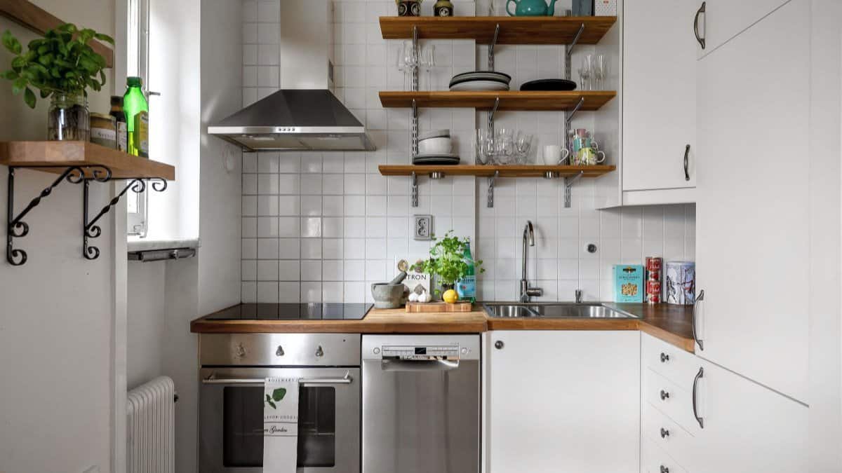 small apartment kitchen with open wall shelves and hooks in daylight