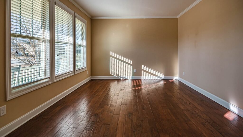 normal wear and tear empty apartment room with hardwood floor and daylight