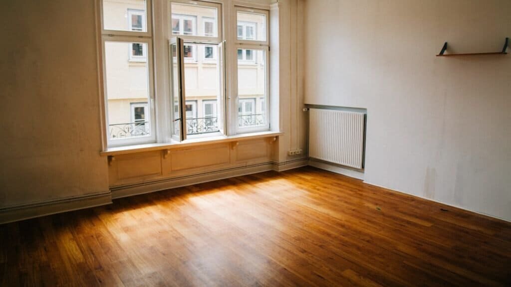 what to check at an apartment viewing: an empty room with tall windows and wood floors